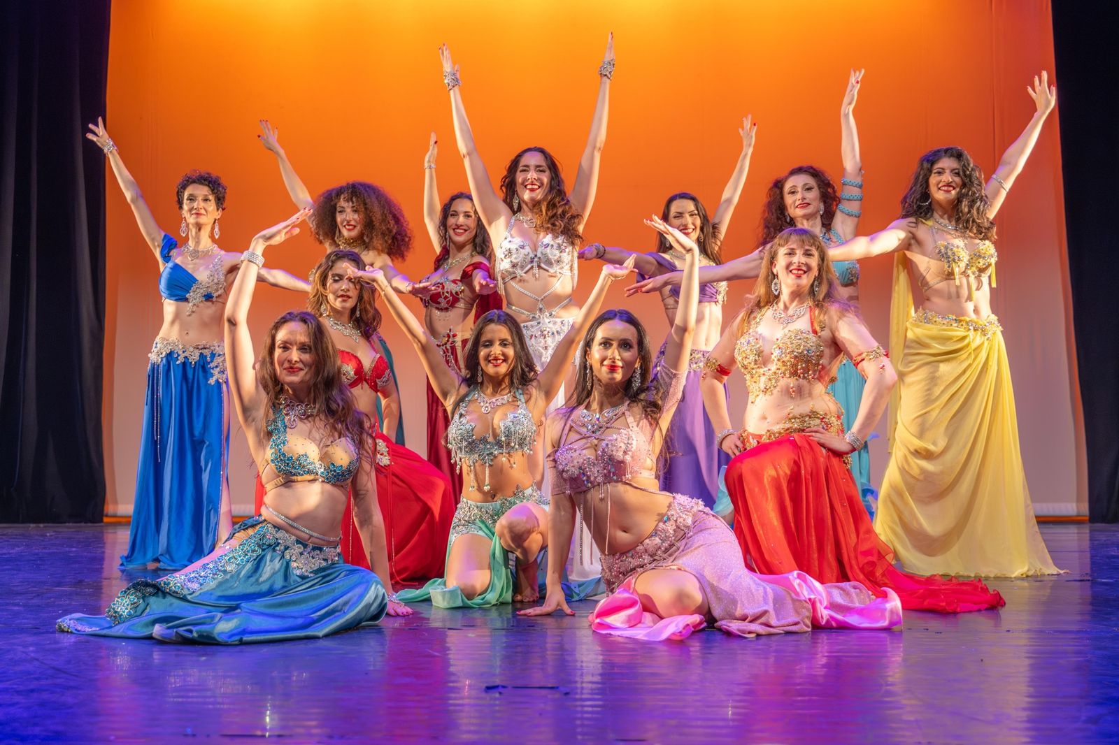 Les danseuses du Ballet Egypt'Ciya en costumes colorés, bras levés sur scène